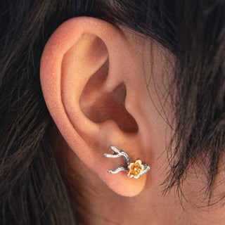 On ear photo of a silver branch earring with bronze flower blossom