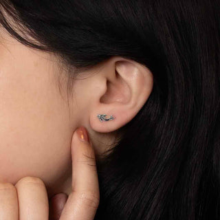 Close-up of an ear with a tiny Koi fish post earring, surrounded by dark hair.