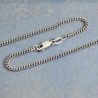 Silver Curb Chain Necklace on a light blue textured background