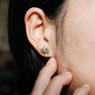 On ear photo of banana earrings where the banana is silver and the peel is bronze