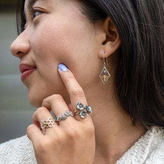 Women wearing silver flower earrings and rings
