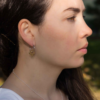 Close-up of a woman wearing a gold earring with a small pendant.