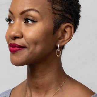 Woman wearing Sterling Silver Oval Huggie Hoop with Bronze Link and necklace against a neutral background