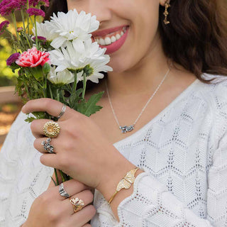 Woman holding flowers and wearing jewelry with a blurred background