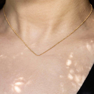 Gold necklace on a person's neck with a neutral background