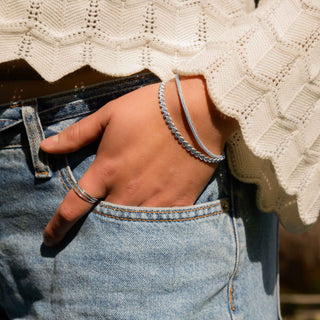 Close-up of a person wearing a silver bracelet and ring, with a blurred background.