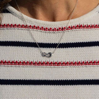 Necklace with an infinity symbol worn by a person wearing a striped sweater.