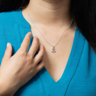 Person wearing a silver necklace with a pendant against a blue shirt