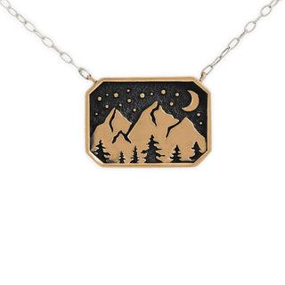 A rectangular pendant necklace with a mountain and forest design, featuring a black night sky with stars and a crescent moon, suspended from a silver link chain on a white background.