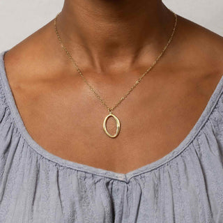 Bronze Asymmetrical Oval Necklace on a person wearing a gray top against a neutral background