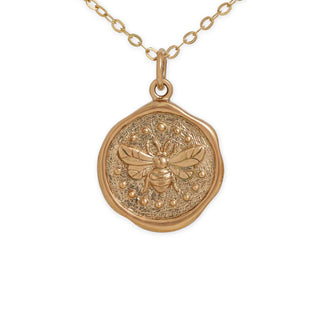 Gold necklace with a bee pendant on a white background