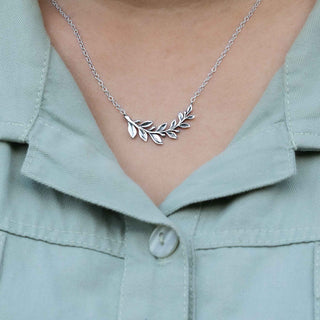 Silver leaf necklace worn by a person in a light green shirt