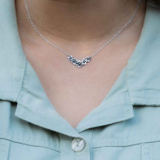 Silver necklace worn by a person with a light blue shirt