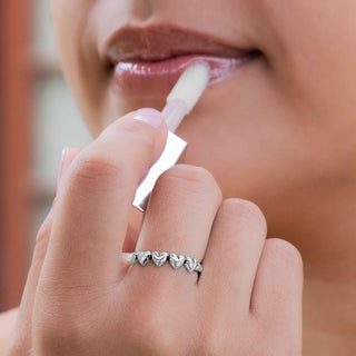 Close-up of a person applying lip balm with a Sterling Silver Five Hearts Ring