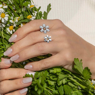 Close-up of a hand wearing silver flower-shaped ring with a bouquet of flowers.