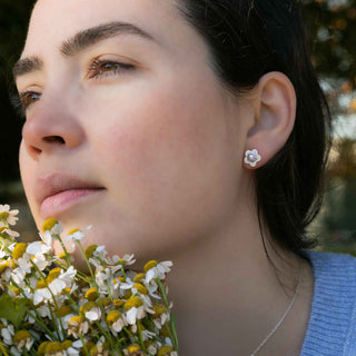 Woman wearing a flower-shaped earring with a blurred natural background