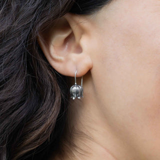 Close-up of a person wearing a silver earring with dark hair.