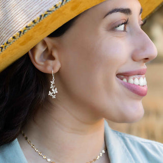 Woman wearing a straw hat and silver earrings with a blurred natural background