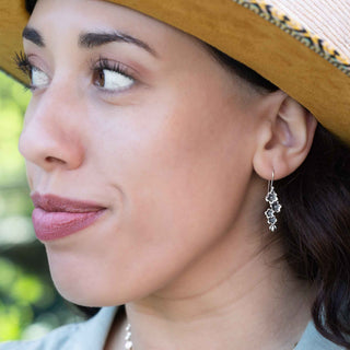 Close-up of a woman wearing a straw hat and silver earrings with a blurred green background
