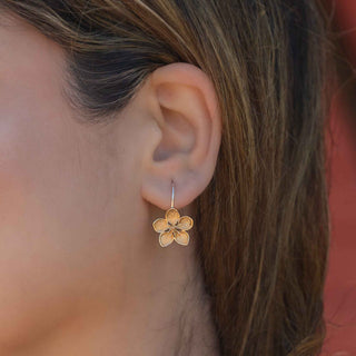 Close up of woman wearing bronze flower earrings