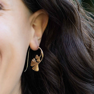 Close-up of a person wearing bronze earrings 