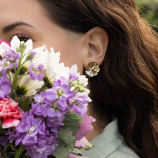 Woman wearing bronze earrings with a bouquet of flowers