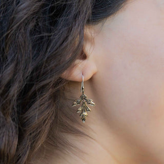 Close-up of a person wearing a leaf-shaped earring with blurred background