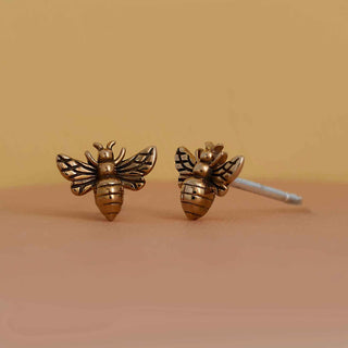 Bronze bee-shaped earrings on a beige background
