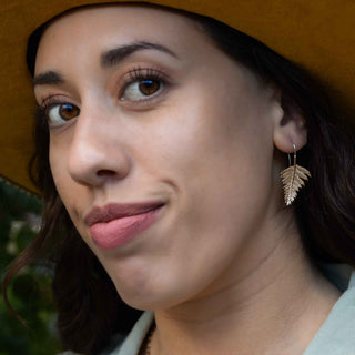 Close-up of a woman wearing a leaf-shaped earring with a blurred background