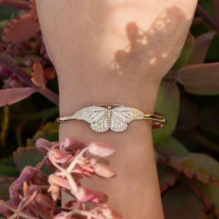 Gold butterfly bracelet on a wrist with a natural background
