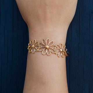 Bronze floral bracelet on a wrist with a dark blue background