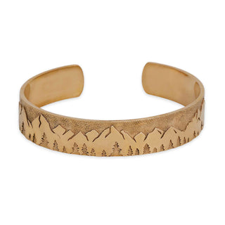 Bronze bracelet with mountain and tree design on a white background