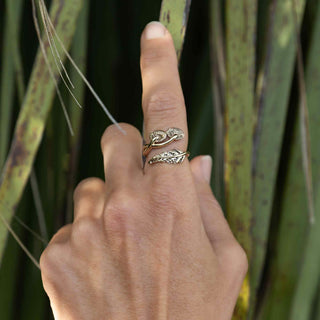 Hand wearing a silver ring with leaf design against a natural background