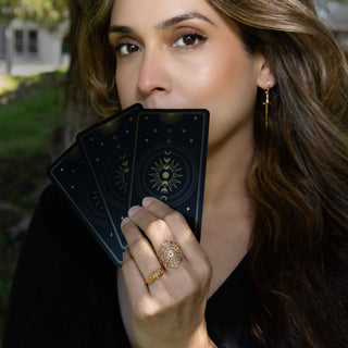 Woman holding tarot cards outdoors with a blurred background