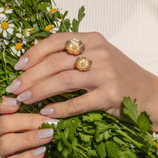 Hand wearing gold flower ring with a bouquet of flowers