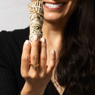 Woman holding sage wearing a bronze bat ring