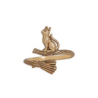 A gold-colored ring featuring a small sculpted cat sitting on a textured broom, set against a plain white background.