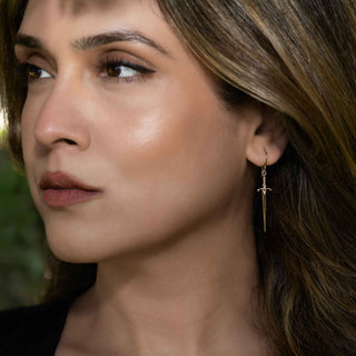 Close-up of a woman wearing a gold earring with a blurred natural background