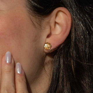 Close-up of a person wearing a gold earring with intricate design.