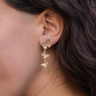 bronze butterfly earrings worn by a person with dark hair.