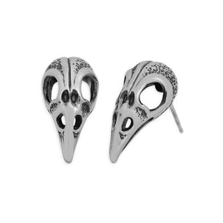 A pair of silver bird skull stud earrings with dark oxidized detailing in the crevices, shown from front and side angles on a plain white background.