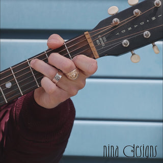 Man playing guitar wearing bronze and silver  rings